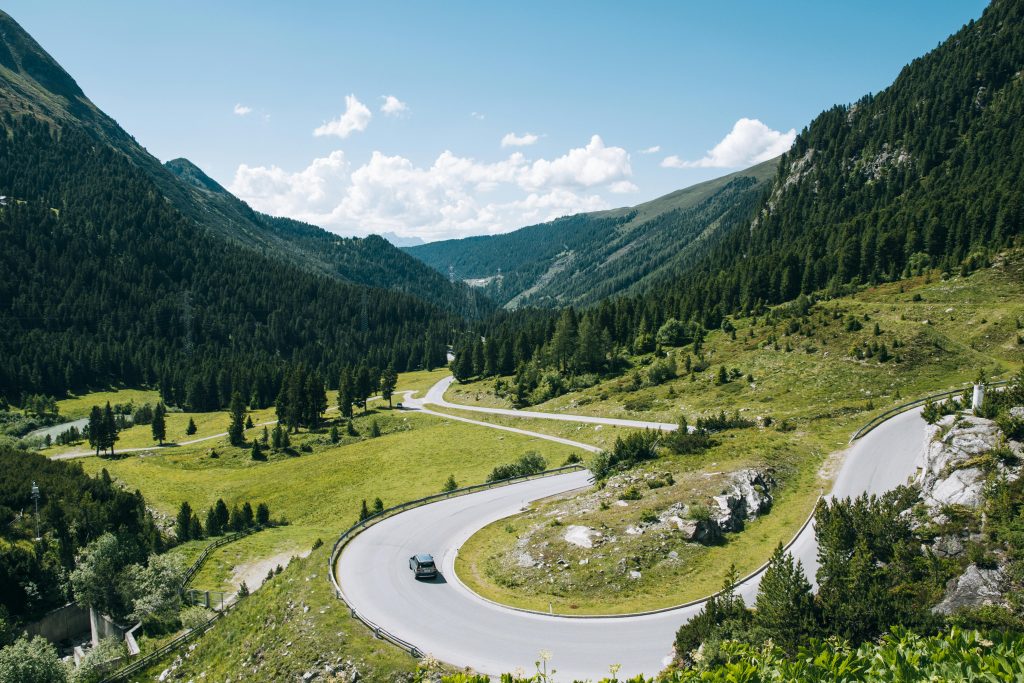 A captivating scenic view of a winding road through the lush green mountains and valleys of Tyrol, Austria.